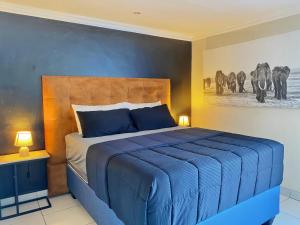 a bedroom with a blue bed and a painting of elephants at Modern Luxe Escape in Kempton Park