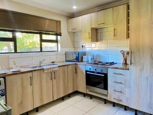a kitchen with wooden cabinets and a stove top oven at Modern Luxe Escape in Kempton Park