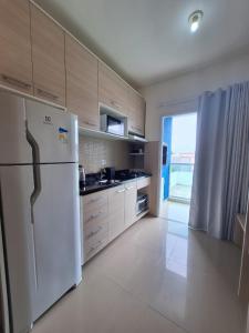 a kitchen with a white refrigerator and a window at Estúdio Fit Caiobá - Matinhos in Matinhos
