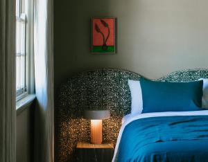 a bedroom with a bed with a blue blanket and a lamp at Sona Molong in Molong