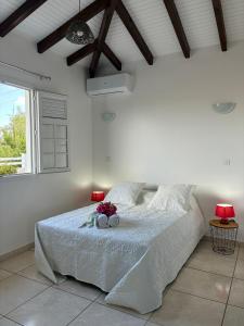 a white bedroom with a bed with flowers on it at Villa Dulce Caliente au Vauclin in Le Vauclin