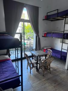 a room with a table and chairs and bunk beds at Real Ros Hostel in Rosario