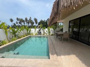 a swimming pool next to a house with a table at Villa Sabaï • Private Pool • Thong Krut in Nathon Bay