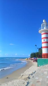 ein Leuchtturm an einem Strand neben dem Meer in der Unterkunft Casa Riso Dourado in Paracuru