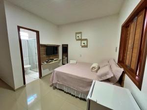 a bedroom with a bed and a bathroom with a television at Pousada Chale Joana in Alter do Chao