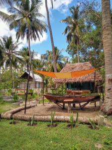 a hut with a hammock in front of palm trees at LalaMafia Bungalow in Utende