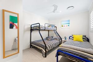 a bedroom with two bunk beds and a mirror at Bec's Beach House Getaway in Batemans Bay