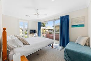 a bedroom with a bed and a couch and a window at Bec's Beach House Getaway in Batemans Bay