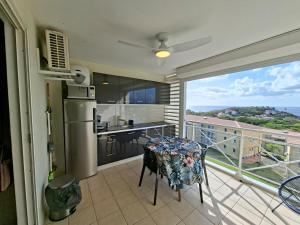 a balcony with a table and a kitchen with a view at Studio vu sur les caraïbes in Les Trois-Îlets