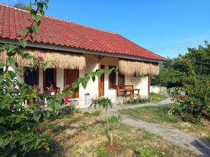 a cottage with a red roof and a person sitting at a table at Ekas Elen Homestay in Pulau Gilkaliantan
