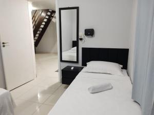 a white bedroom with a bed and a mirror at Casa Paraíso Piscina Aquecida e Pet Friendly in Sinop +41 photos