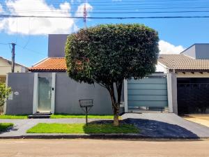 a tree in front of a house with a garage at Casa Paraíso Piscina Aquecida e Pet Friendly in Sinop