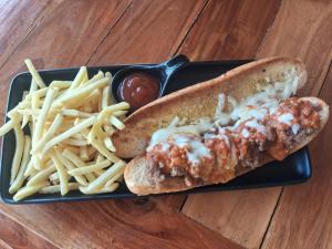 a black plate with a hot dog and french fries at Isaan Country Retreat in Mukdahan