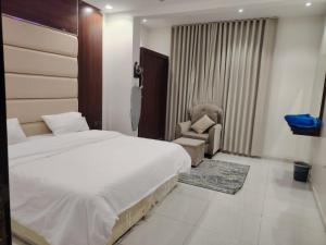 ein Schlafzimmer mit einem Bett und einem Stuhl in einem Zimmer in der Unterkunft ميلاف للشقق المخدومة Milaf For Serviced Apartments in Al Shafa