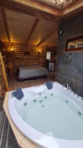 a large bath tub in a room with a bed at Cabañas Refugio del Lago in El Cerrillo