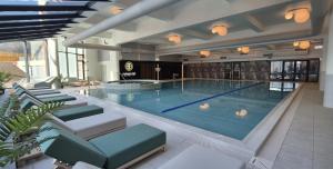 a large swimming pool in a building with chairs at Elma Studio Sinaia - spa si piscina contra cost in Sinaia