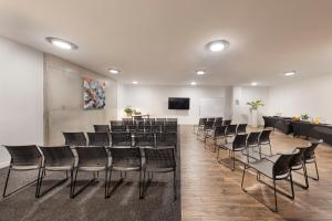 a room with a bunch of chairs and a bar at BreakFree on Cashel, an Accor Hotel in Christchurch