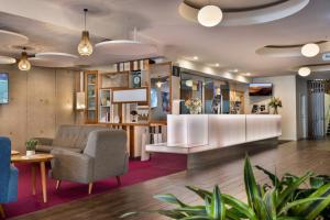 a lobby with a waiting area with chairs and tables at BreakFree on Cashel, an Accor Hotel in Christchurch