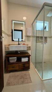 a bathroom with a sink and a glass shower at Apartamento de 2 quartos no centro de Garopaba in Garopaba