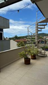 a balcony with two potted plants on a building at Apartamento de 2 quartos no centro de Garopaba in Garopaba