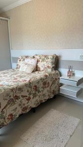 a bedroom with a bed with a floral bedspread and pillows at Apartamento de 2 quartos no centro de Garopaba in Garopaba