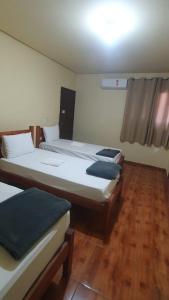 two beds in a room with wooden floors at Norte Minas Hotel in Bocaiúva