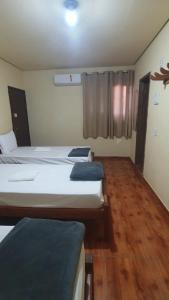two beds in a room with wooden floors at Norte Minas Hotel in Bocaiúva