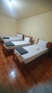 two beds in a room with wooden floors at Norte Minas Hotel in Bocaiúva