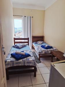 two beds in a room with a window at Pousada Morada in Aparecida