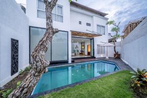a swimming pool in the backyard of a house with a tree at The Dewi Pererenan Villa and Suite in Tumbak Bayuh