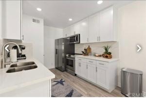 a kitchen with white cabinets and a stainless steel refrigerator at Beach Condo in Dana Point