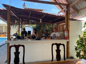 Eine Gruppe von Menschen sitzt an einer Bar in der Unterkunft HostalElCascolManabiPuertolopez in Puerto López