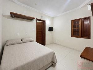 a bedroom with a bed and a wooden cabinet at Pousada Miriam in Limeira