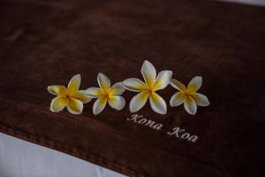 three white and yellow flowers on a brown towel at Kona Koa Lodge in Hanga Roa