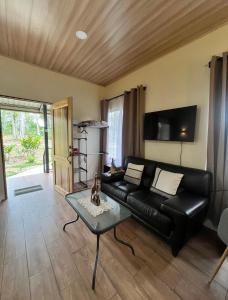 a living room with a black leather couch and a table at Cabañas y Senderos Finca El Triunfo in Los Chiles