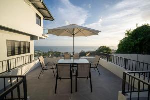 a patio with a table and an umbrella on a balcony at Avaya Oasis - Suriname Suite in Carenage