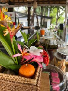 a basket with flowers and an orange on a table at Royal Regantris Villa Karang in Gili Islands