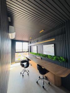 an office with a long desk with chairs and plants at Flat Exclusivo com Rooftop e Piscina in Campina Grande +50 photos