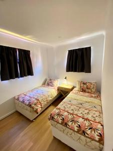 two beds in a small room with a bedskirts at Sunlodge Caravan Park in Hervey Bay