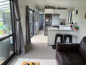 a living room with a couch and a kitchen at BB'S Cabin in Kerikeri +17 photos