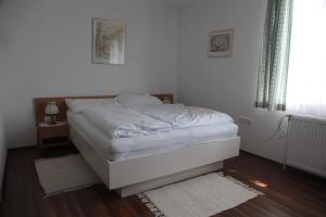 uma cama branca num quarto com piso em madeira em Pension Casa Topolino em Wiener Neustadt