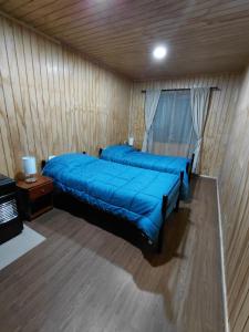 a bedroom with a blue bed in a wooden room at Siloe in Coihaique