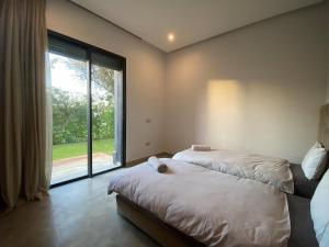 a bedroom with two beds and a large window at Villa nomad marrakech in Douar bel Rhanodour