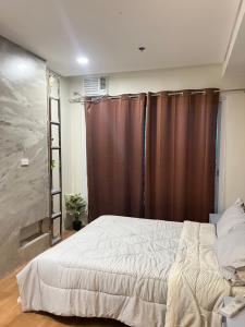 a bedroom with a large bed and brown curtains at Primavera Citta Verde in Balulang