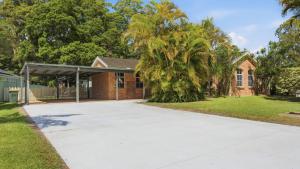 a driveway in front of a house with a palm tree at Boater's Retreat - pet friendly, right off the M1 in Toormina