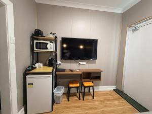 a room with a desk with a computer and a tv at Alpine Heritage Motel in Goulburn