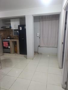 a kitchen with a black refrigerator and a white tile floor at Minidepartamento Centro de Huanuco in Huánuco