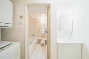 a white bathroom with a tub and a sink at 照間Terumaの美しい海Mareまで徒歩30秒リビング広々快適 TERUMAREテルマーレ in Uruma +62 photos
