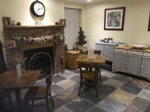 a living room with a fireplace and a table and chairs at Deri-Down Guest House in Abergavenny