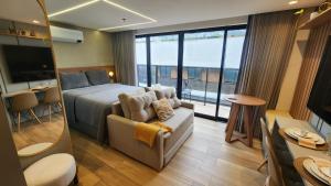 a bedroom with a bed and a couch and a table at Flat 410 Luxo com Varanda e Vista Mar l Frente Mar Orla de Cabo Branco I Setai Edition in João Pessoa